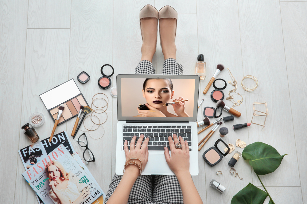 woman on laptop surrounded by beauty tools 