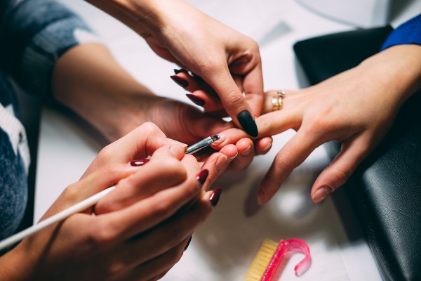 two hands painting the nails of someone else