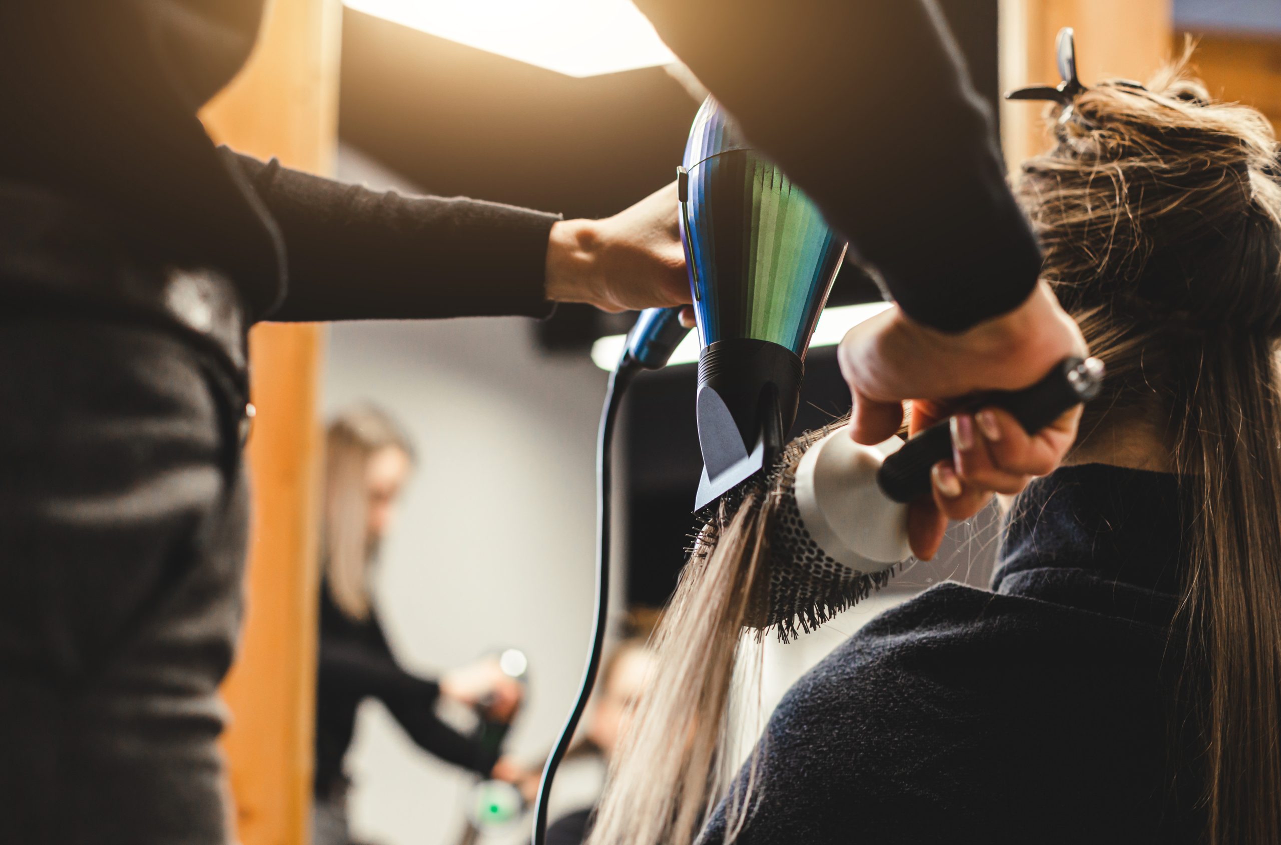 Woman hairdresser dries the girl's hair with a hairdryer after washing in a beauty salon